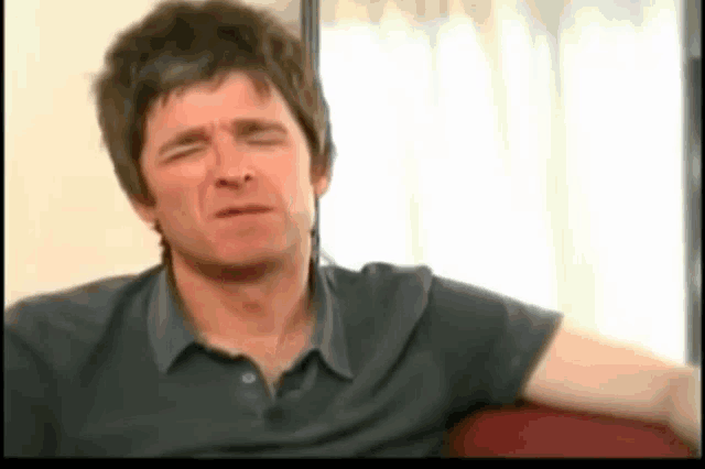 a man in a black shirt is sitting on a couch with his eyes closed