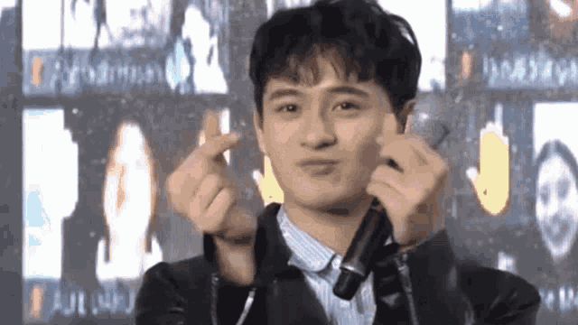 a young man in a leather jacket is making a heart shape with his fingers .