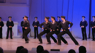 a group of men in sailor uniforms are dancing on stage