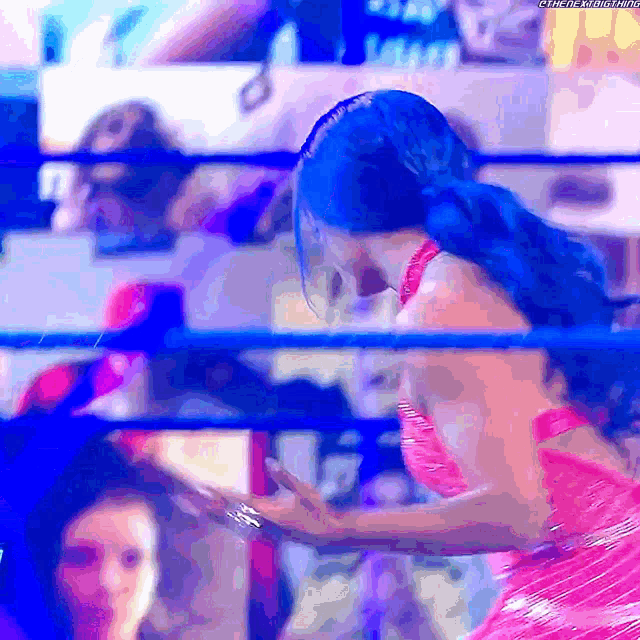 a woman in a pink dress is standing in a ring with a blue background
