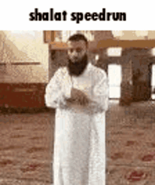 a man with a beard is standing in a mosque with his hands folded .