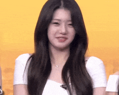 a woman with long black hair is smiling and wearing a white shirt