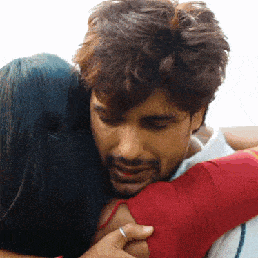 a man with a ring on his finger is hugging a woman in a red dress