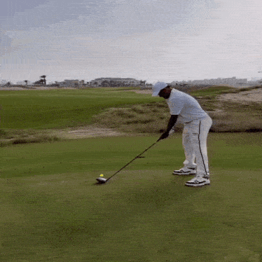 a man swinging a golf club on a golf course wearing a white shirt that says bmw