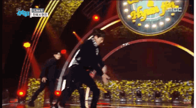 a group of men are dancing on a stage with a sign that says like it