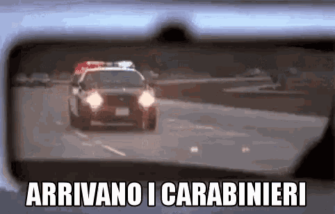 a police car is driving down a highway in front of a rear view mirror .