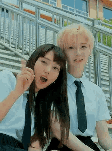 two young women in school uniforms and ties are sitting next to each other on a bench .