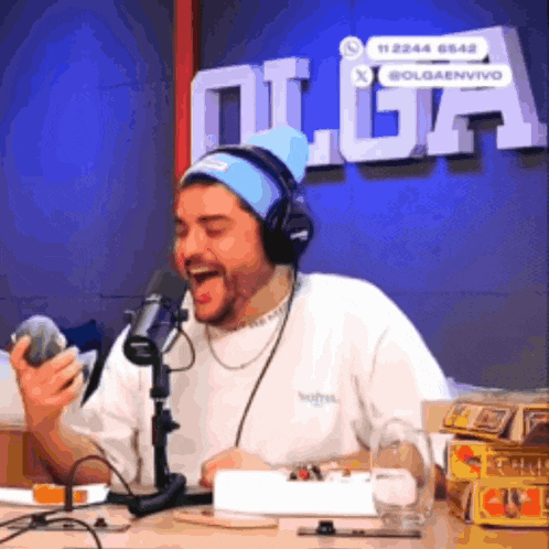 a man wearing headphones and a beanie is sitting in front of a microphone in front of the word olga