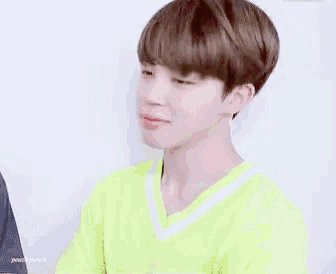 a close up of a person wearing a neon yellow shirt and earrings .