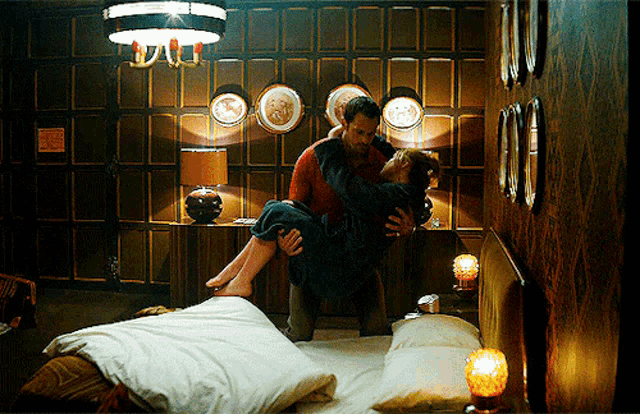 a man is holding a woman in his arms in a bedroom with a sign on the wall that says no smoking