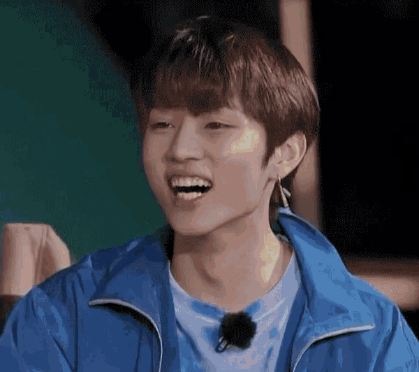 a young boy wearing a blue jacket and a tie dye shirt is smiling .