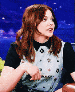 a woman with red hair is wearing a black and white shirt