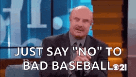 a man in a suit and tie is sitting on a couch and saying `` just say no '' to bad baseball .