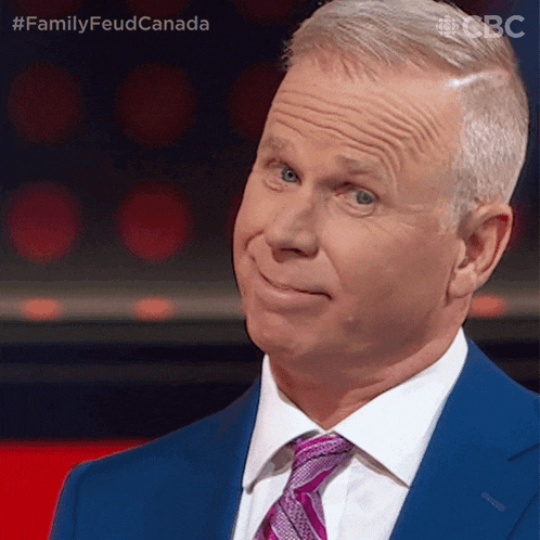 a man in a suit and tie is looking at the camera with the caption familyfeud canada