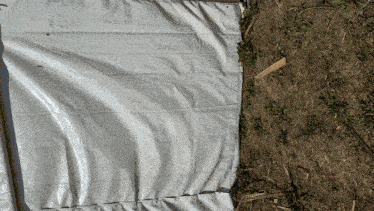 a white tarp is laying on the ground next to a wooden stick