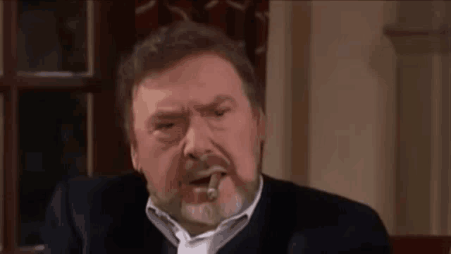 a man with a beard is smoking a cigar and making a funny face .
