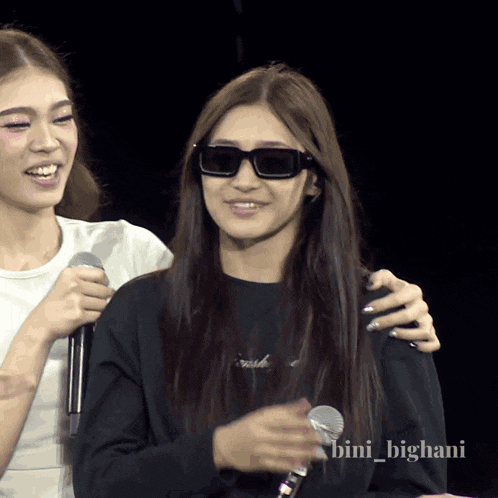 a woman wearing sunglasses and a black sweater with the name bini_bighani on it