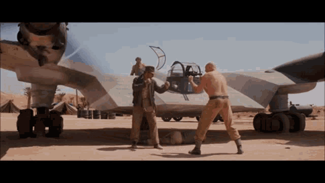 two men are standing in front of a plane in a field
