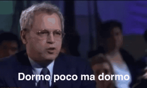 a man in a suit and tie says dormo poco ma dormo in front of a crowd