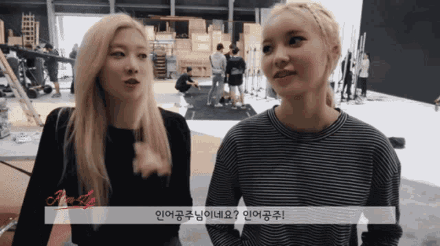 two blonde women are standing next to each other and one of them is wearing a black and white striped sweater