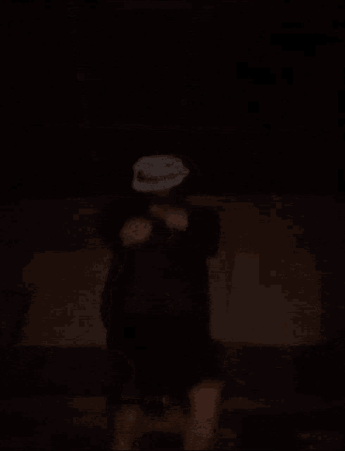 a person with a mask on their head is dancing in a dark room