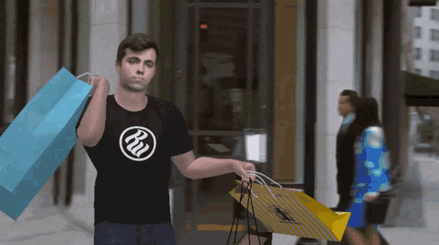 a man wearing a t-shirt with the letter rw on it is carrying shopping bags