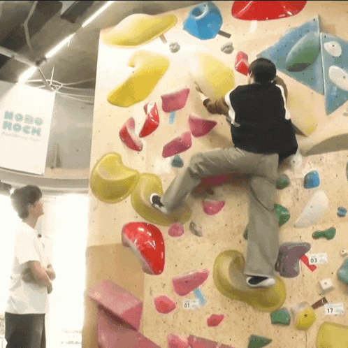 a man climbs a climbing wall in front of a sign that says mono rock