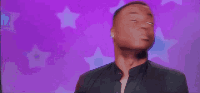 a man is standing in front of a purple background with stars .