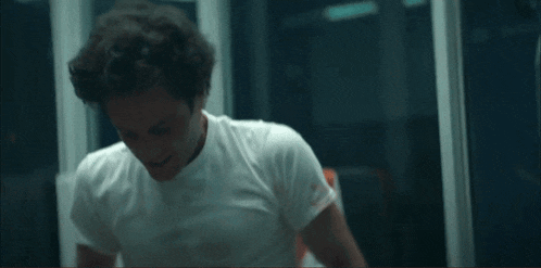 a man in a white shirt is holding his hands to his head
