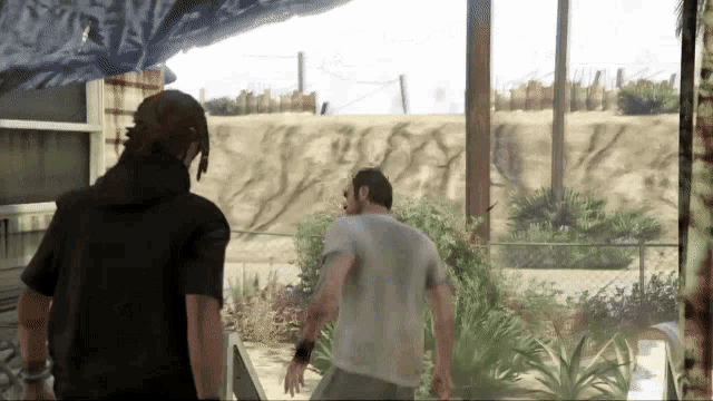 a man in a black hoodie stands next to a man in a white shirt