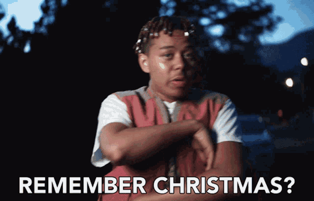 a man in a red vest says " remember christmas " in white letters