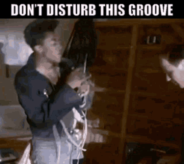 a man is playing a guitar in a room with the words do n't disturb this groove on the bottom