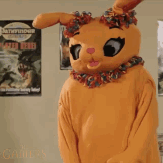 a stuffed animal in an orange bunny costume is dancing in a room with posters on the wall .