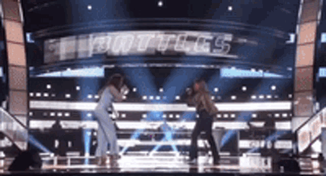 a man and a woman are dancing on a stage in front of a sign that says ' bottles '