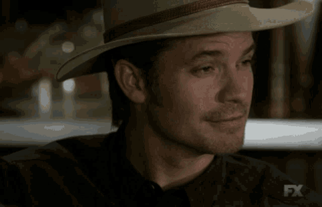 a man wearing a cowboy hat is smiling and the fx logo is visible behind him