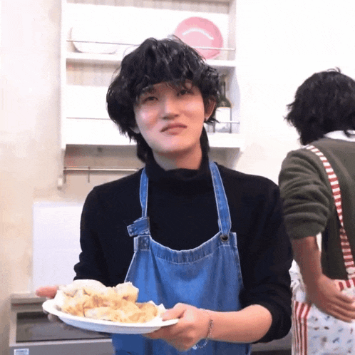 a person wearing an apron holds a plate of food