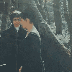 a man and woman kissing in the woods