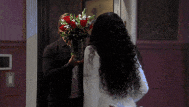 a man is holding a vase of flowers in front of his face