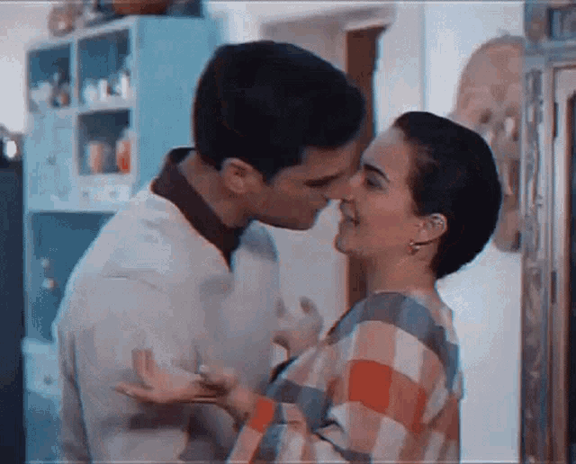 a man kissing a woman on the forehead in a kitchen .