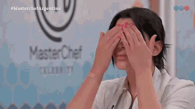 a woman is covering her eyes in front of a masterchef logo