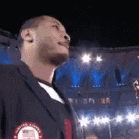 a man wearing a united states olympics jacket is standing in a stadium
