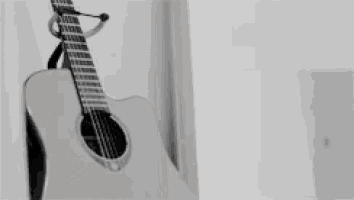 a guitar is hanging on a hook on a white wall