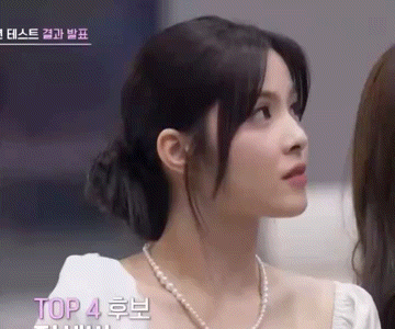 a close up of a woman wearing a pearl necklace and a white top .