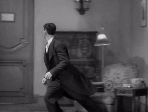 a black and white photo of a man in a suit running
