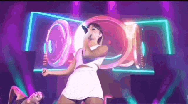 a woman in a white dress is singing into a microphone