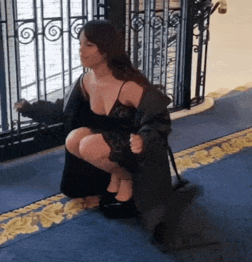 a woman in a black dress is squatting down
