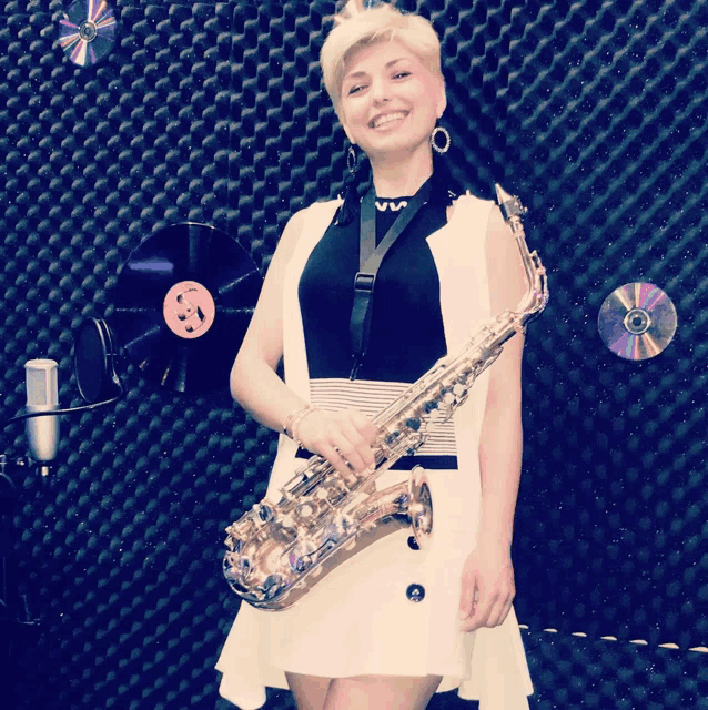 a woman holding a saxophone in front of a wall with cds and records on it
