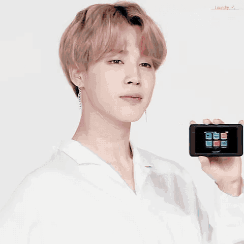 a man in a white shirt is holding a cell phone in his hand and the word laundry is on the bottom right