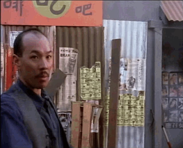 a bald man stands in front of a building with a sign that says ' ao ' on it