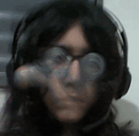 a woman wearing headphones and glasses holds a bottle in her hand